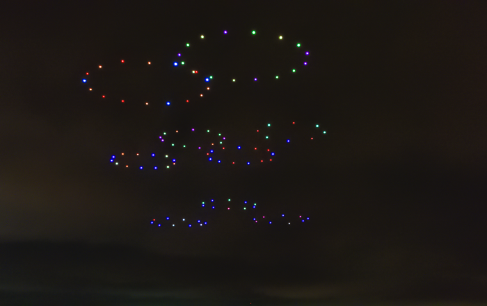 drone performance with nine coloured rings formed by illuminated drones in the sky